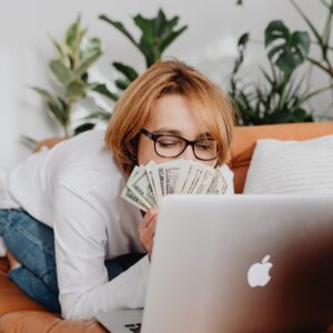 girl holding money while using her laptop